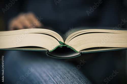 woman in blue jeans holding a book and reading