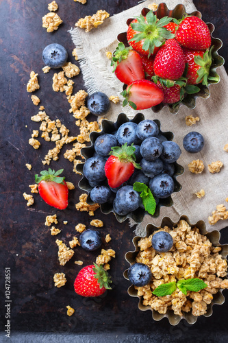 Homemade muesli granola in bowl with berries on rusty table