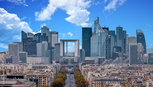 La Defense Financial District Paris France in autumn. Traffic on Champs-Elysees with orange and yellow trees aside. Modern vs. Old architecture. Blue sky with clouds.