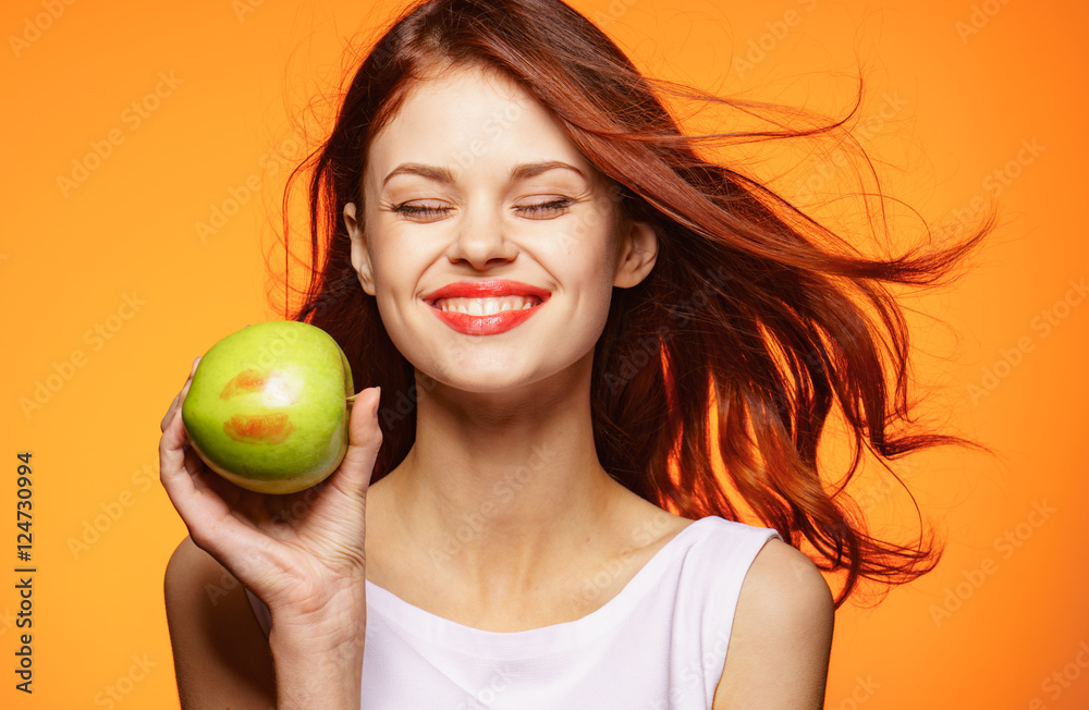Woman on an orange background with an apple in her hand
Woman on an orange background with an apple in her hand