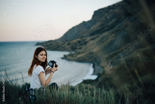 Woman with a camera in the hands in the mountains