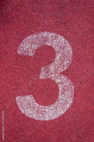 Number three on running track. White track number on red rubber racetrack, texture of running racetracks in stadium