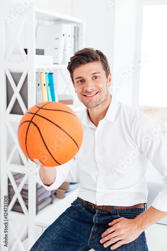 Handsome businessman sitting at the table and holding ball