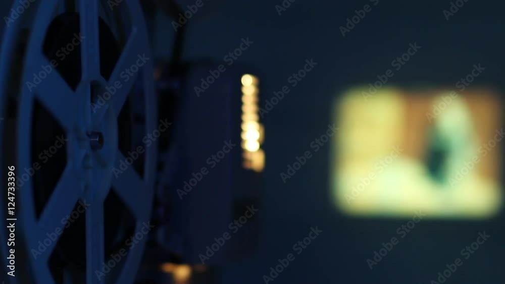 Film projector projecting a movie on the wall with dark blue light