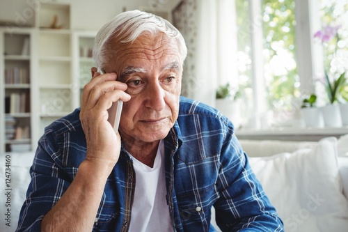 Фотография Tensed senior man talking on mobile phone