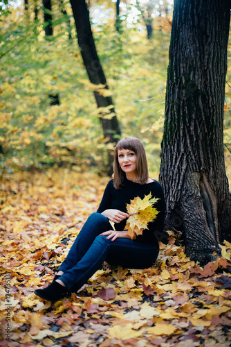 girl sitting near a tree in an autumn maple forest