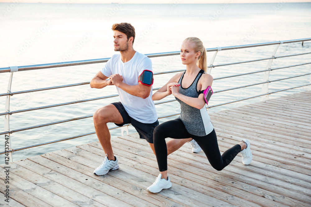 Athletic young couple sitting and stretching legs together