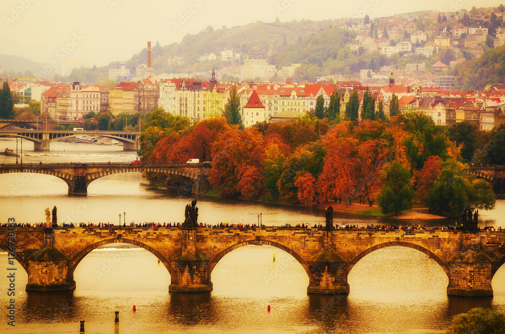 Naklejka premium Center of Prague city at autumn with red roofs and Charles Bridge over river Vltava, european travel landscape background in vintage style