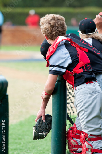 Baseball catcher leaning over dugout fence