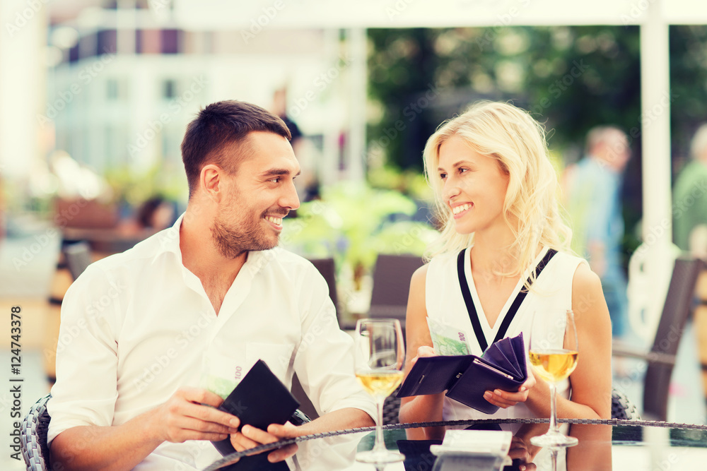 happy couple with wallet paying bill at restaurant happy couple with wallet paying bill at restaurant