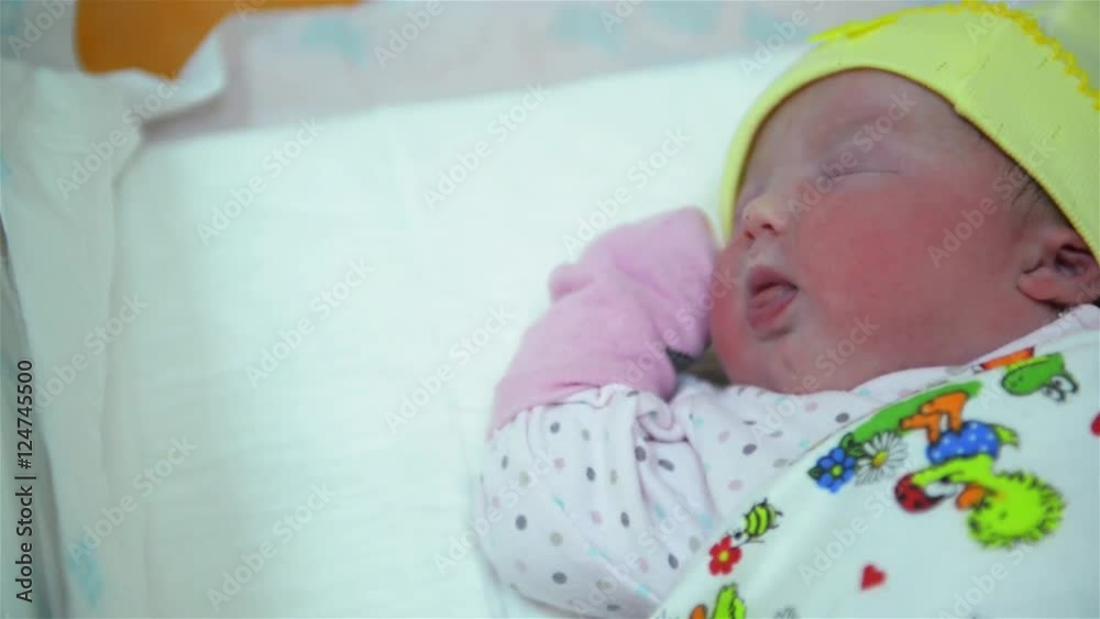 New born infant asleep in the blanket in delivery room, baby girl crying immediately after birth