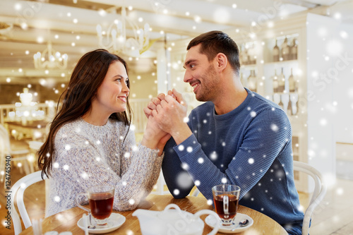 happy couple with tea holding hands at restaurant