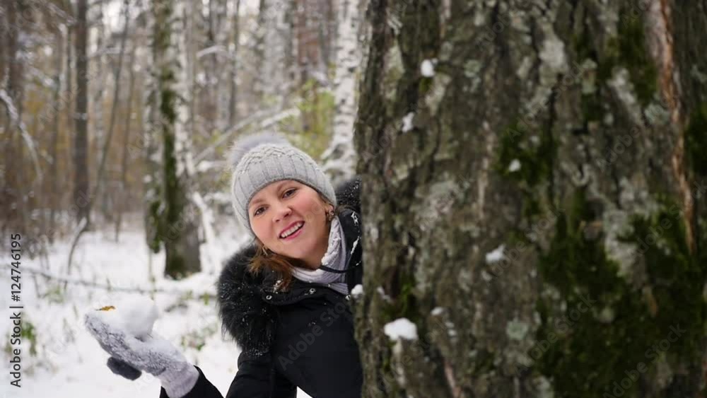 girl playing by throwing snowballs from behind tree in the winter Park girl playing by throwing snowballs from behind tree in the winter Park