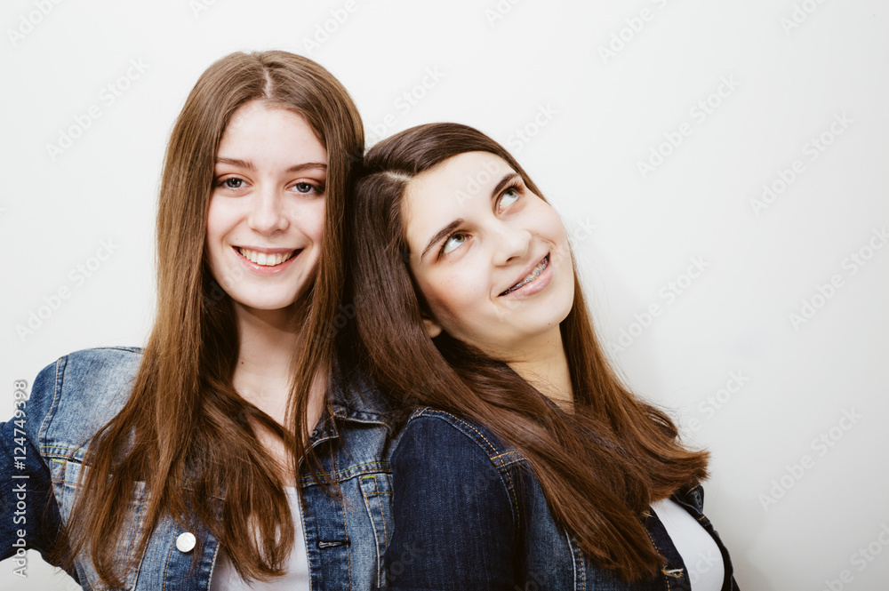fashion photo of two beautiful young women with long dark hair and bright makeup wears casual clothes,posing in studio fashion photo of two beautiful young women with long dark hair and bright makeup wears casual clothes,posing in studio