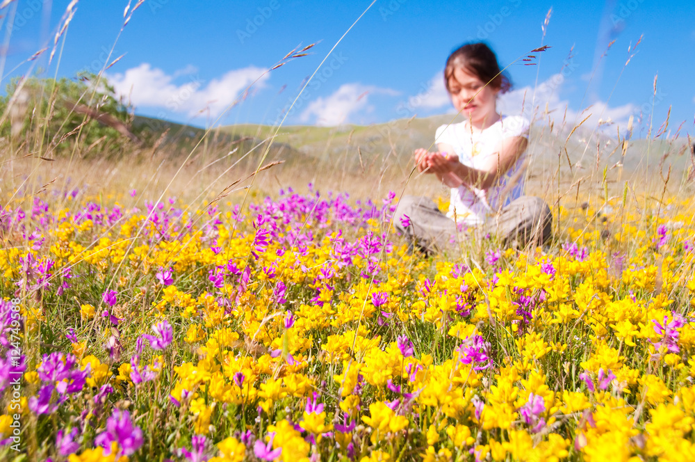 Fototapeta premium Girl sitting in a field of wild flowers