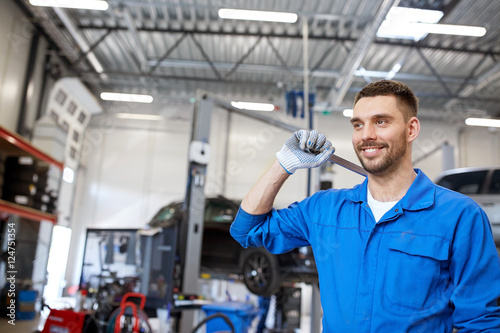 auto mechanic or smith with wrench at car workshop