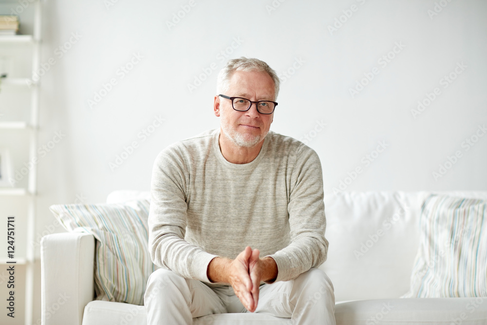 smiling senior man in glasses sitting on sofa