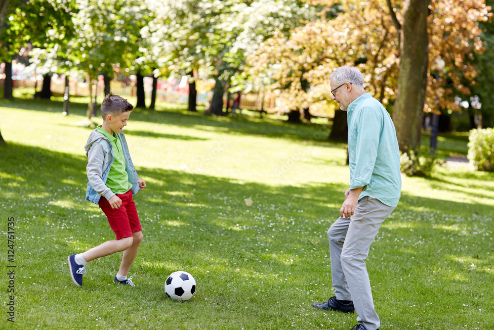 old man and boy playing football at summer park old man and boy playing football at summer park