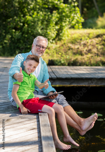 grandfather and boy with tablet pc on river berth
