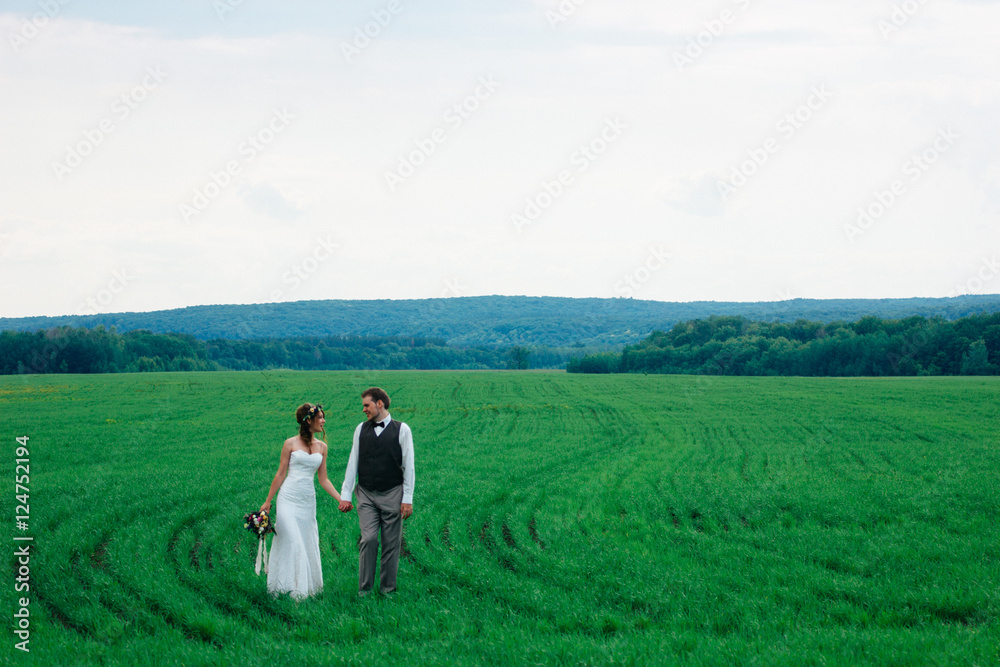 the bride and groom with a bouquet on the green field the bride and groom with a bouquet on the green field
