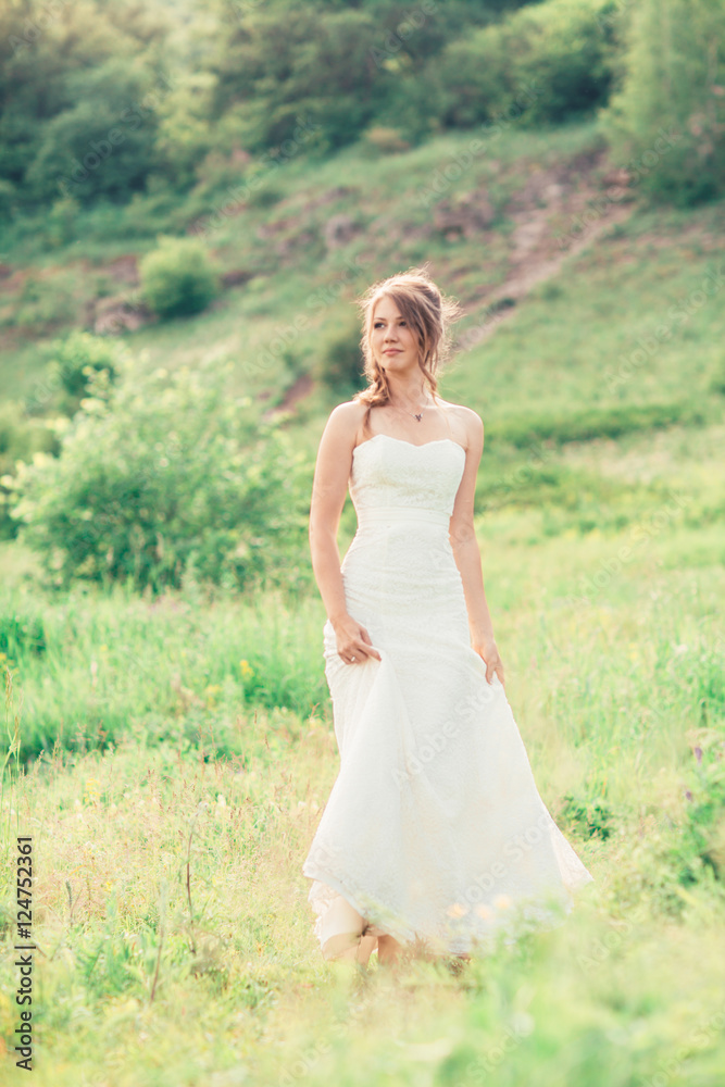 bride stands on a background of grass and mountains