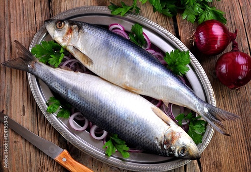 salted herring with red onion and parsley on the old wooden background.