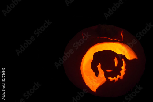 Illuminated scary face halloween pumpkin on black background