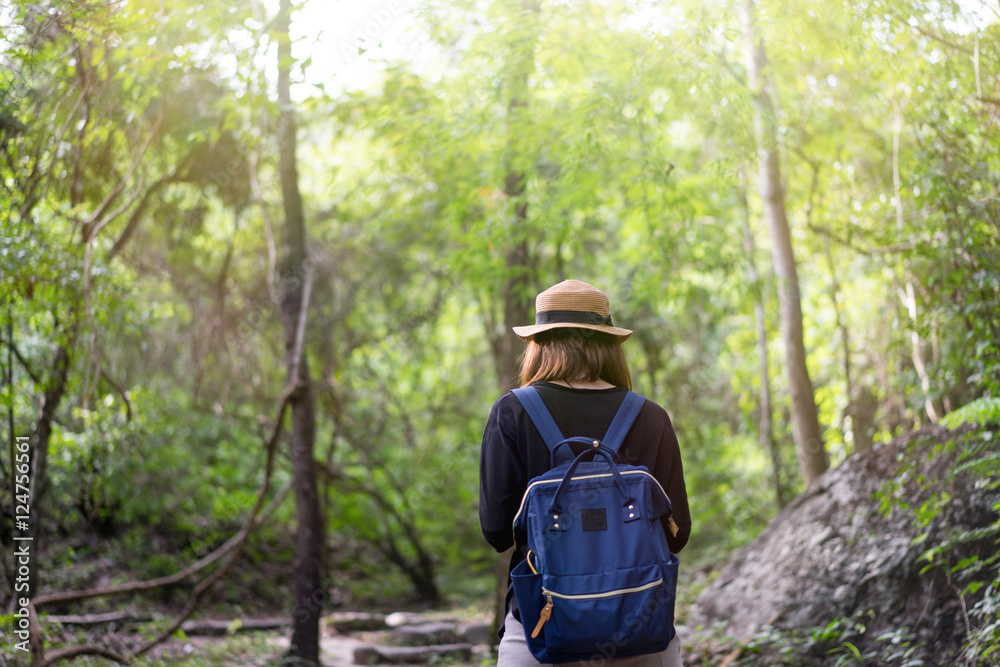 Woman with backpack standing near big tropical forest