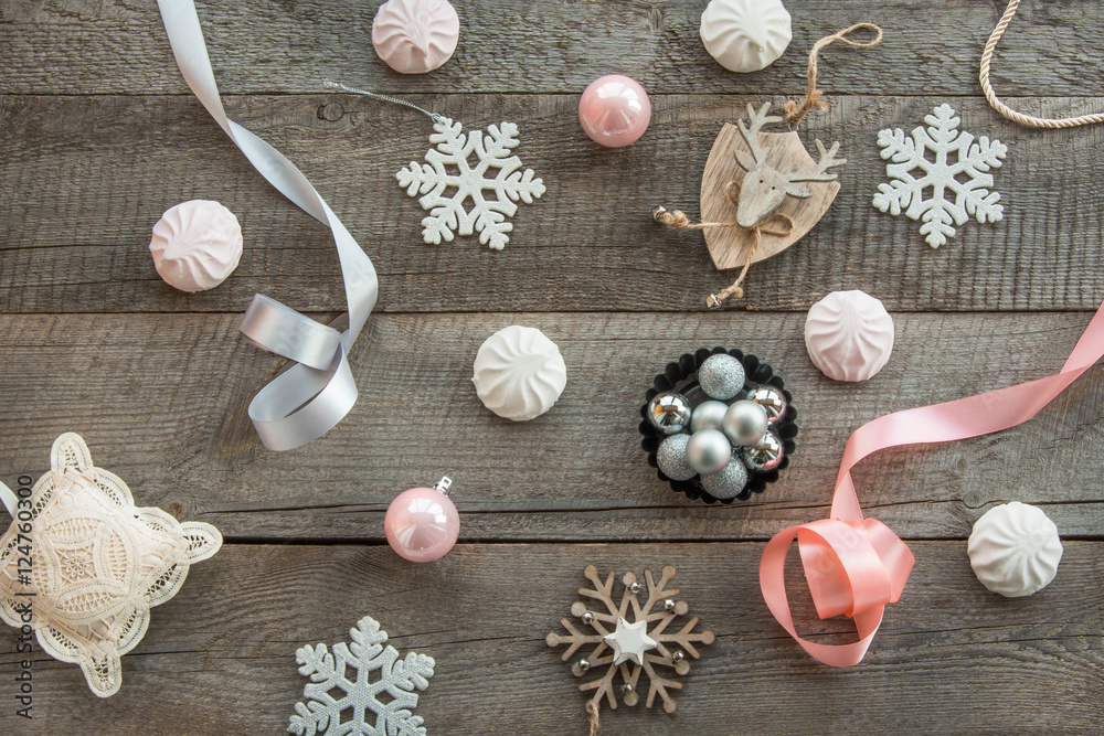 Christmas decor laid out on a wooden surface. Fir branches, pink/silver ribbon and ball, white marshmallow, snowflakes, toy deer and decor around. Top view and copyspace. Flat lay. Shabby-chic Christmas decor laid out on a wooden surface. Fir branches, pink/silver ribbon and ball, white marshmallow, snowflakes, toy deer and decor around. Top view and copyspace. Flat lay. Shabby-chic