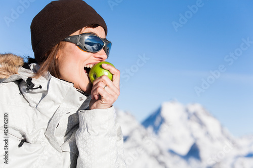 femme à la neige en hiver qui mange une pomme photo