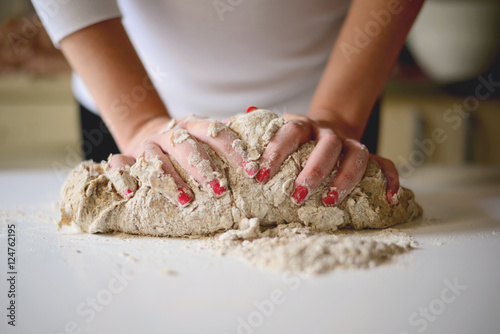 Woman's hands knead dough on a table