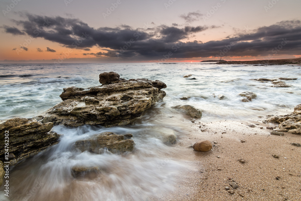 Sunset with waves crashing on the rocks and the lighthouse of Tr Sunset with waves crashing on the rocks and the lighthouse of Tr