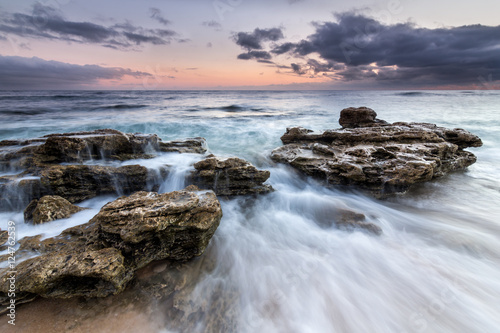 Waves crashing over rocks at sunset on the coast of Trafalgar.