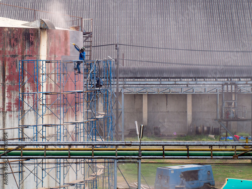 Worker cleaning storage tank by air pressure sand blasting.