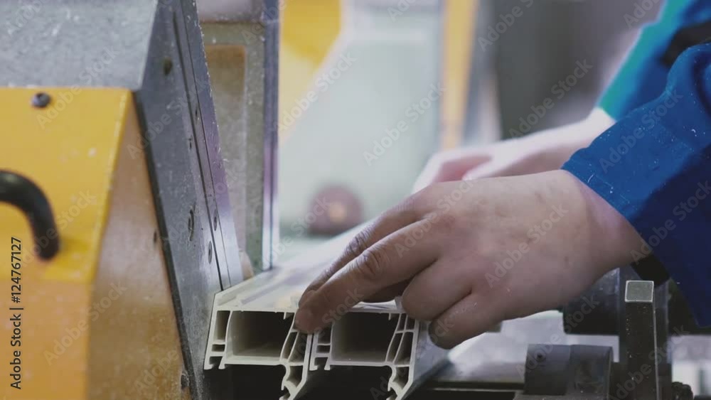 PVC Windows and Doors Manufacturing.Worker cutting PVC profile with