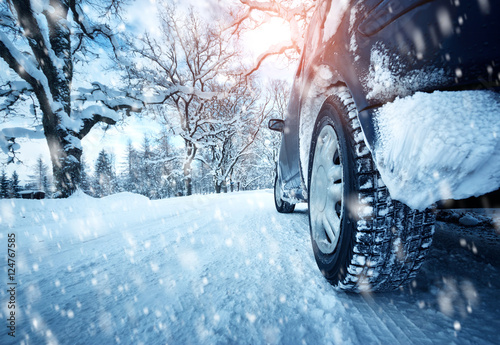 Car tires on winter road covered with snow. Vehicle on snowy alley in the morning at snowfall © candy1812
