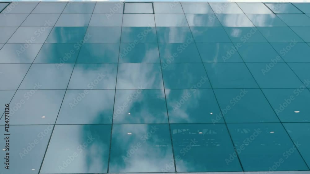 Reflection of blue sky and white clouds on the mirror surface of the glass windows in high-rise building. Dolly shot Reflection of blue sky and white clouds on the mirror surface of the glass windows in high-rise building. Dolly shot
