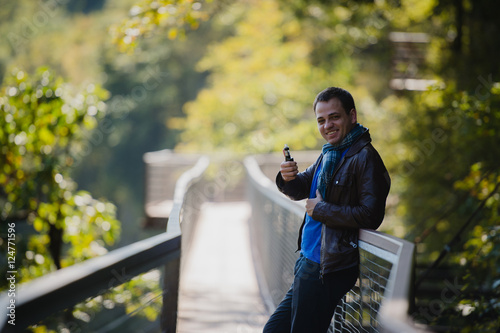 Young man with custom box mode vape device vaping an electronic cigarette outdoor at beautiful place outdoors photo