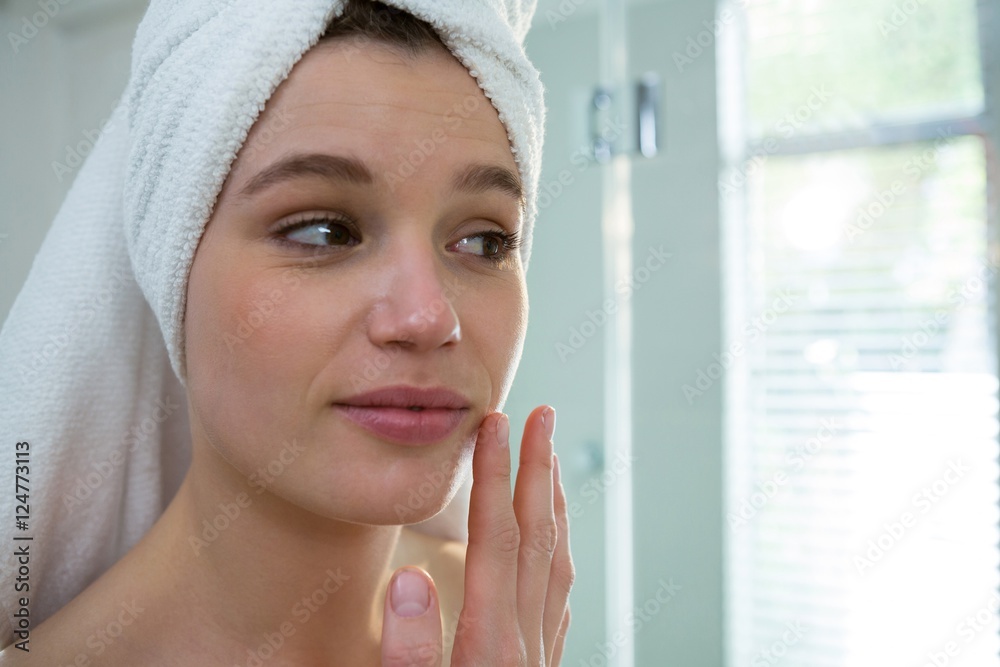 Woman applying moisturizer cream on her face in bathroom Woman applying moisturizer cream on her face in bathroom