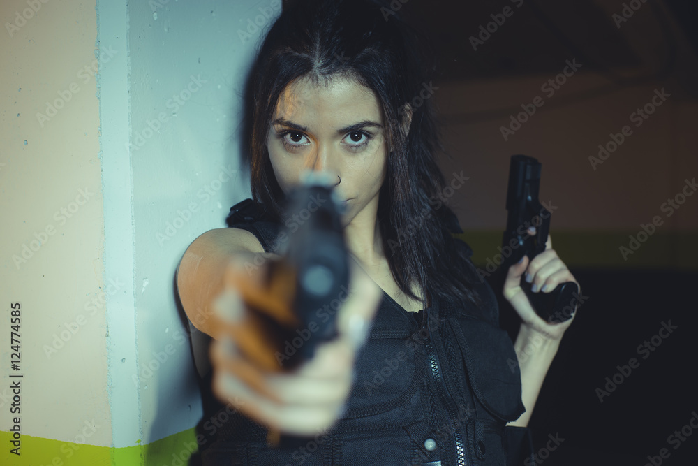 Army brunette girl with gun in a garage in attitude shoot, dress Army brunette girl with gun in a garage in attitude shoot, dress