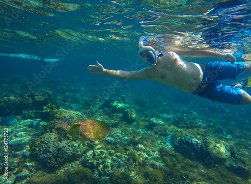 Snorkeling man with sea turtle in tropical lagoon
