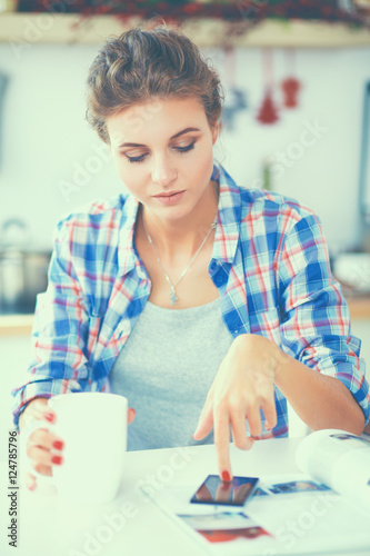 Woman reading mgazine In kitchen at home photo