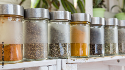 Spices, seasonings in small glass jars on wooden box