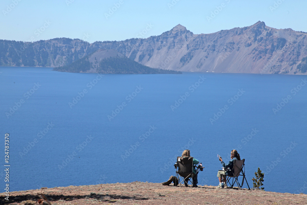 women sitting by lake