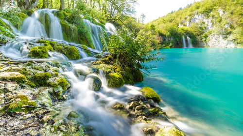 Ein kleiner Wasserfall in dem Kroatischen Nationalpark Plitvice der sich durch die Felsen schlängelt und dann in den türkisen See mündet photo