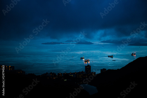 Ships sailing on Hong Kong bay at night in a cloudy sky