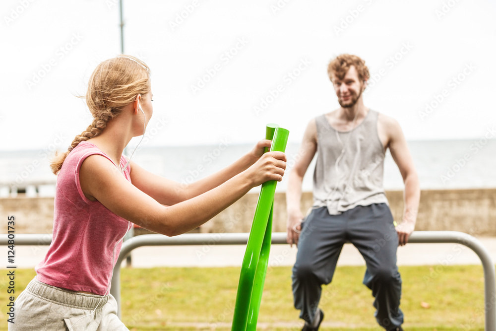Fototapeta premium Man and woman exercising on elliptical trainer.