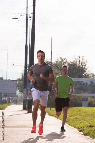 Two young men jogging through the city