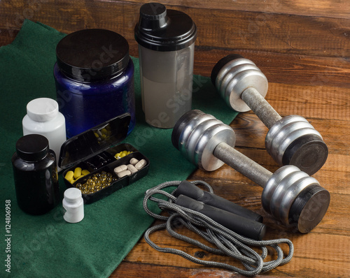 Sport and Fitness Supplement, dumbbells on wood background