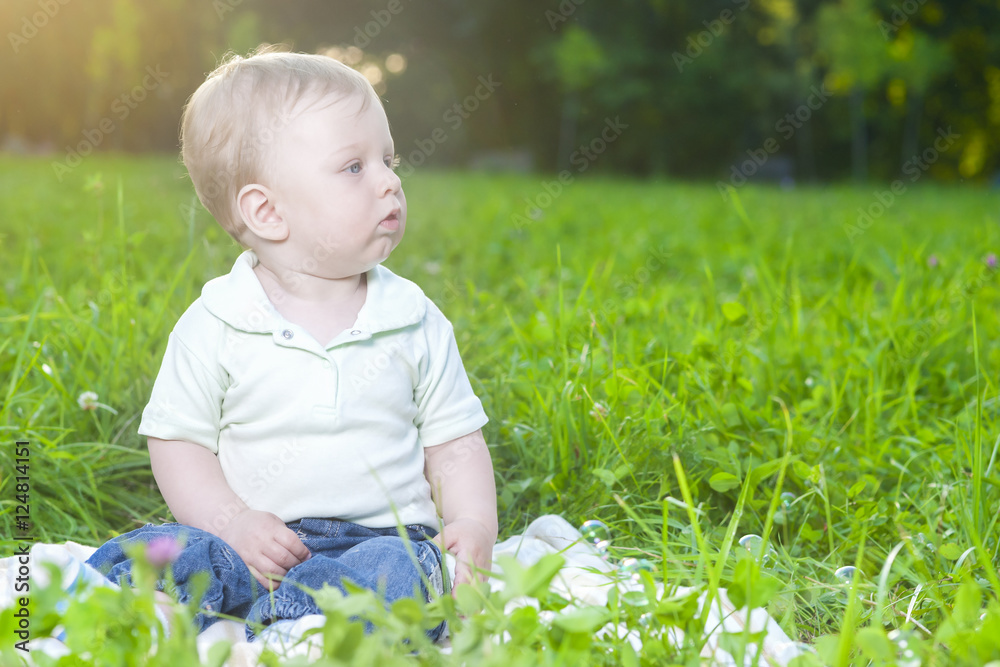Portrait of Little Cute Caucasian Boy Sitting Alone on Grass Outdoors Portrait of Little Cute Caucasian Boy Sitting Alone on Grass Outdoors